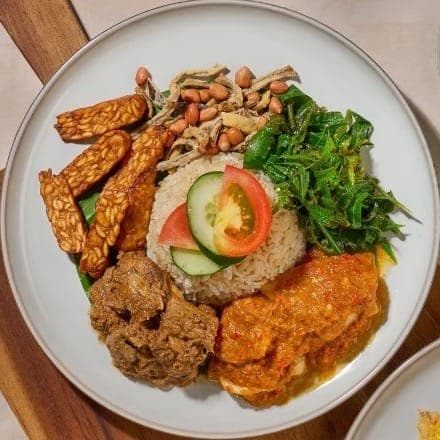 Savor nasi lemak with coconut rice, sambal, tempeh, peanuts, greens and rendang
